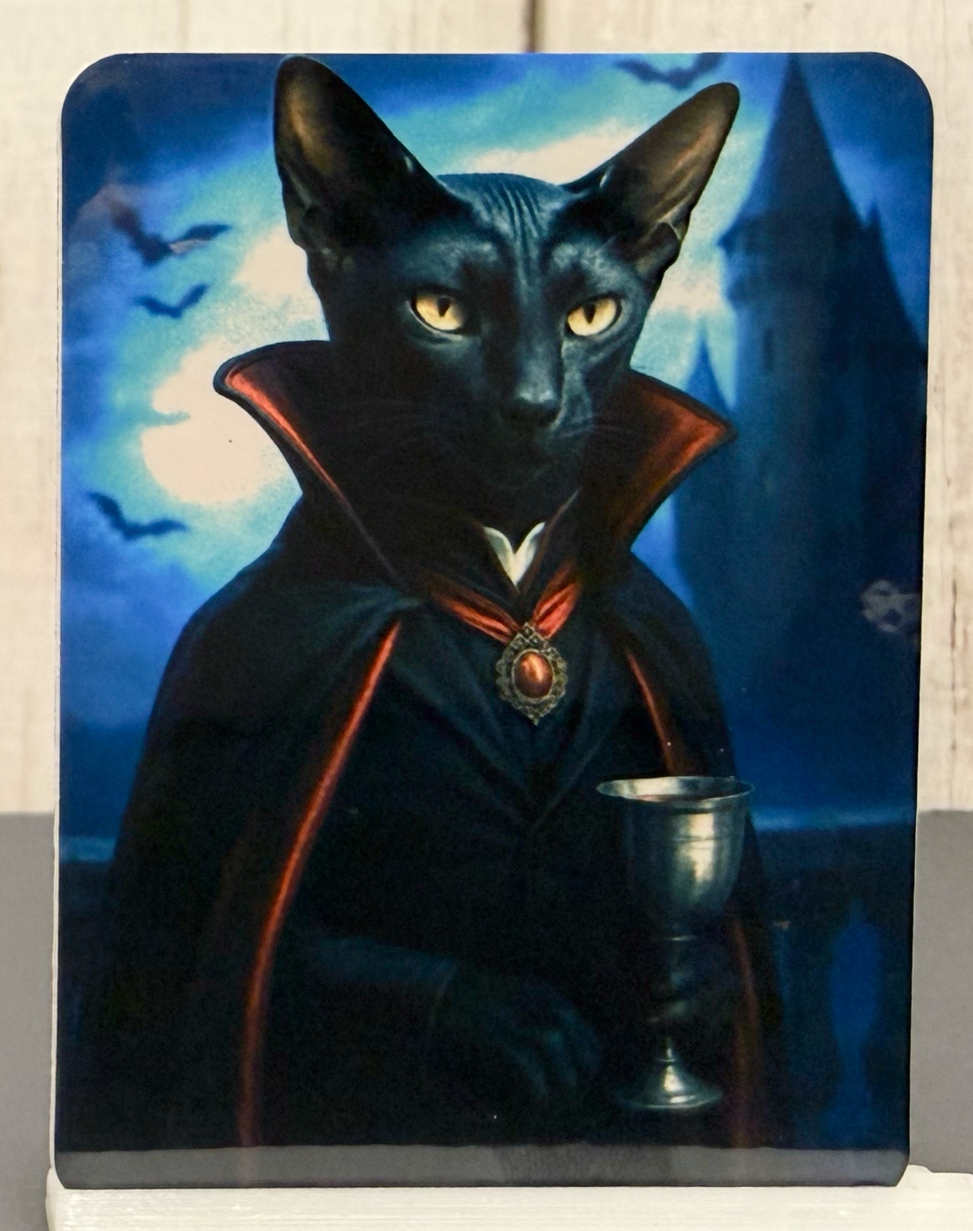 Magnet featuring a vampire cat in a cape holding a chalice against a mystical background