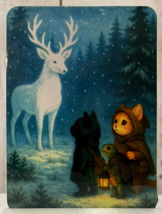 A magnet featuring two cats and a turtle who encounter a winter spirit shaped like a deer.