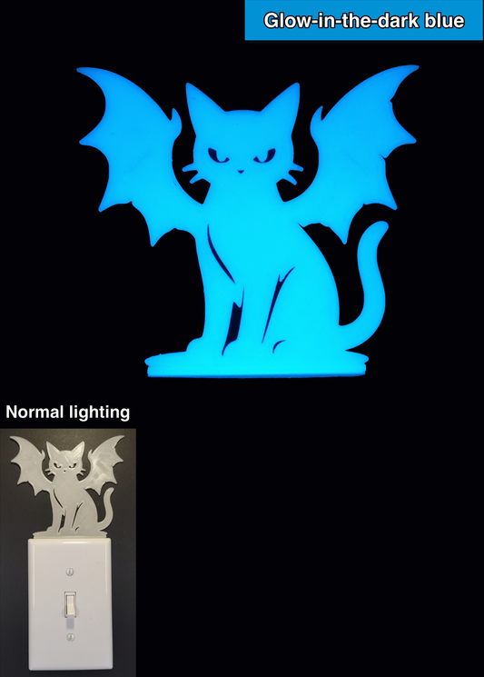 Glowplate light switch finder: glow-in-the-dark blue cat with bat wings, shown in normal lighting and glow-in-the-dark conditions.