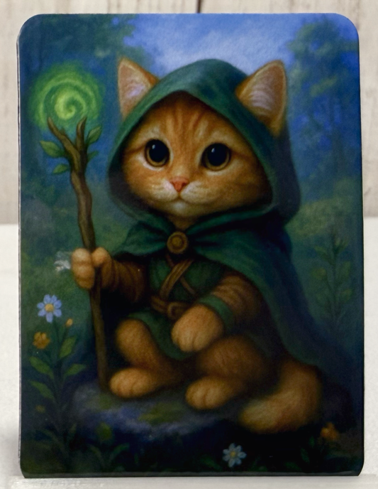 Magnet featuring a druid cat in a green hood holding a staff with a spiral design, surrounded by nature.