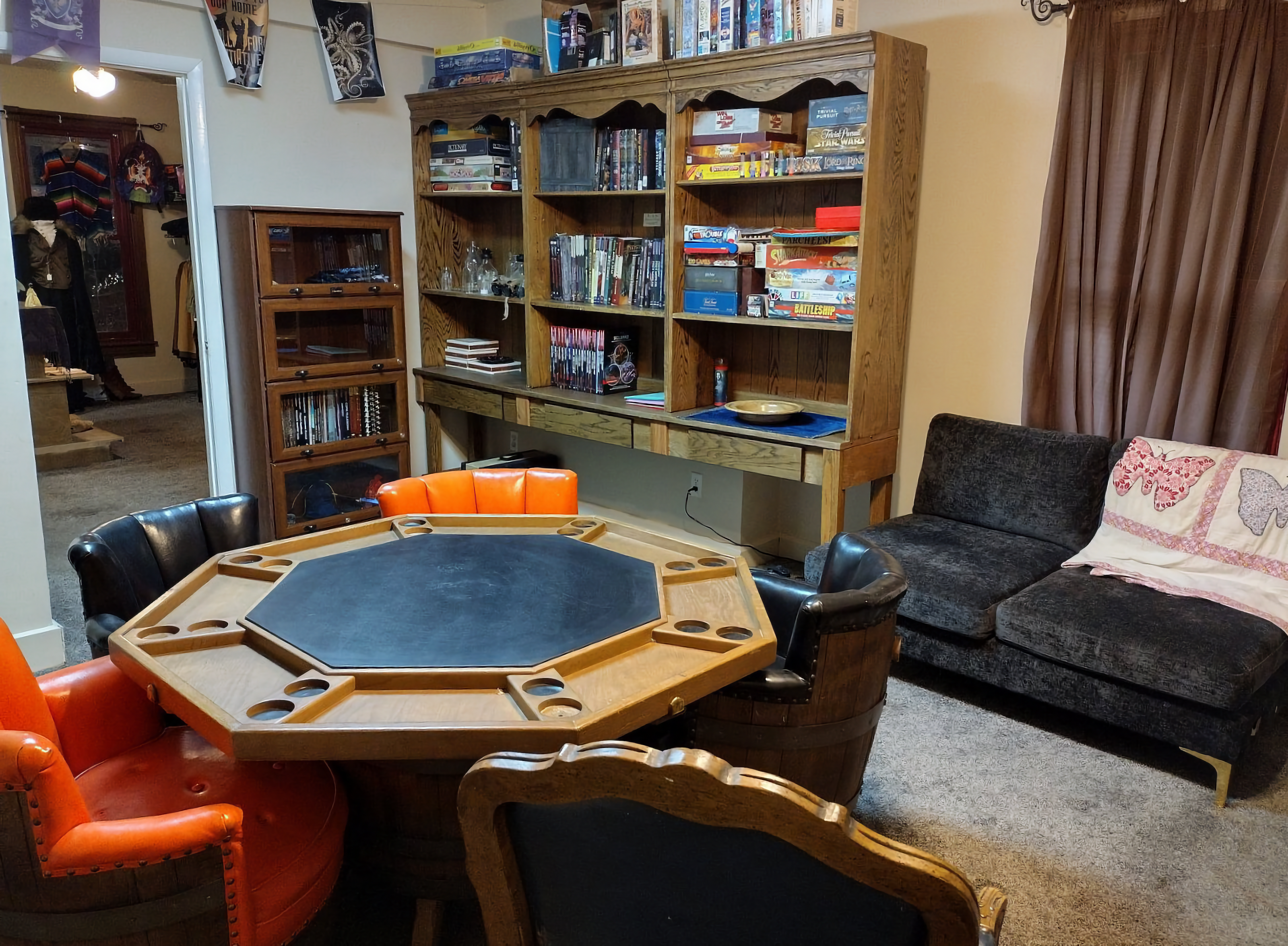Free game room with a card table, chairs, and bookshelves filled with TTRPG resources.