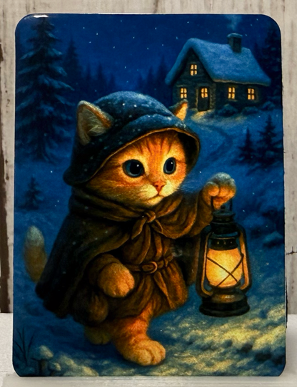 Magnet featuring a cat in a hood and coat holding a lantern in a snowy landscape with a house in the background.