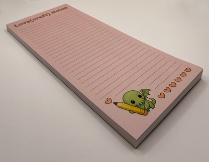 Love(craft) Notes - lined notepad featuring chibi Cthulhu holding a pencil, drawing hearts