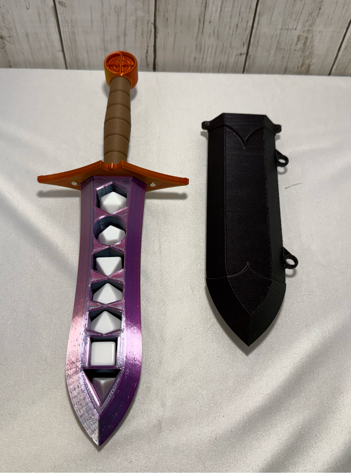 3D-printed dice sword with pink blade, orange pommel, brown handle, and matching sheath.