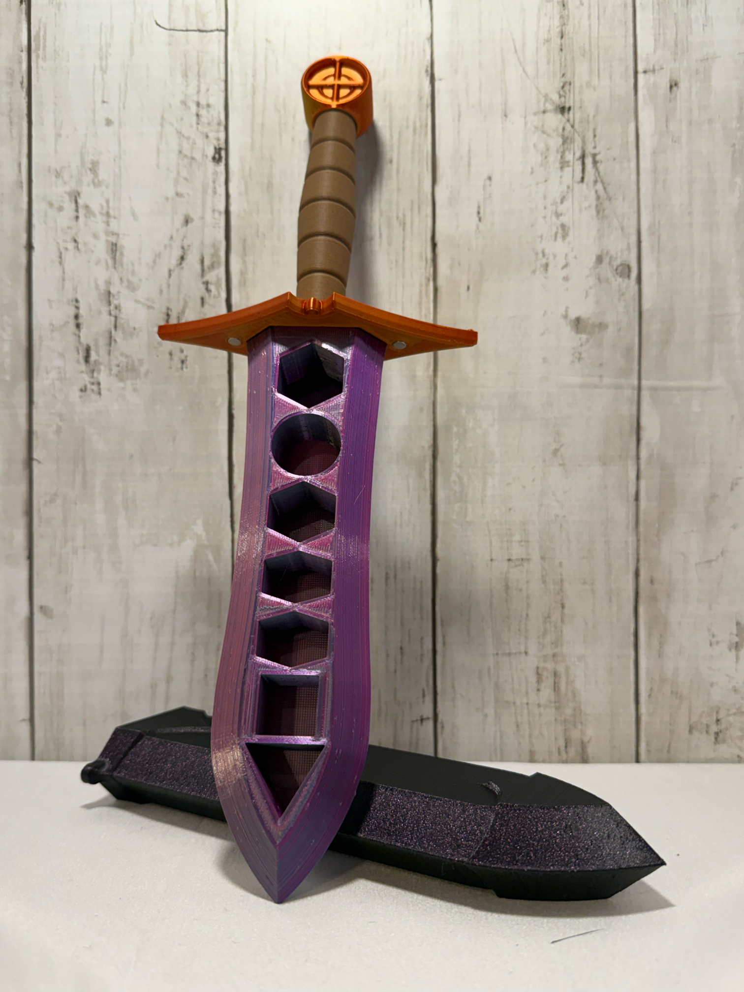 3D-printed dice sword with pink blade, orange pommel, brown handle, and matching sheath.