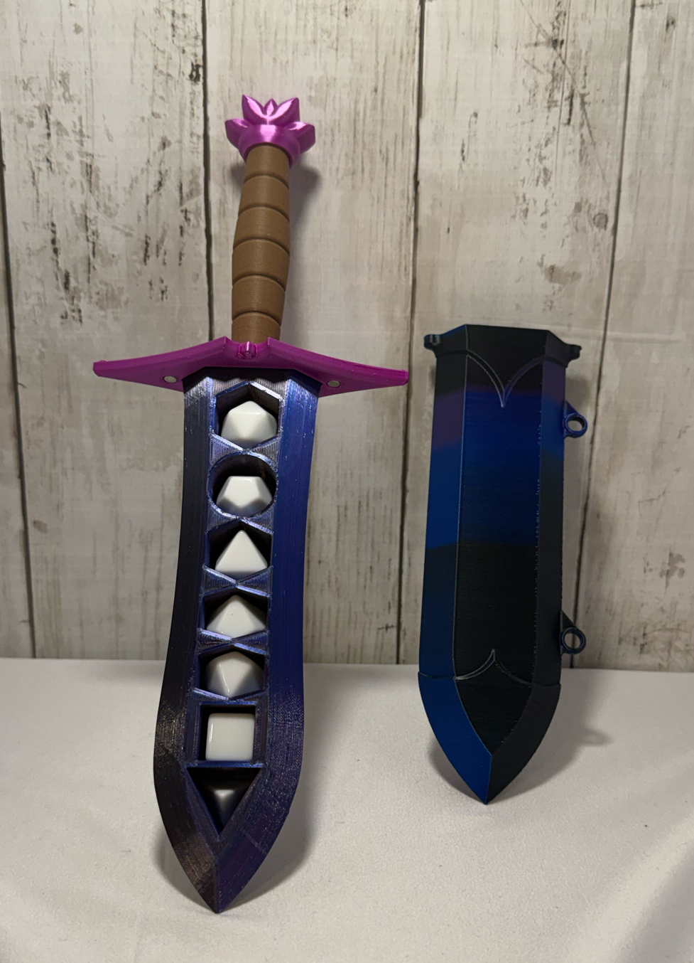 3D-printed dice sword with purple blade, pink pommel, brown handle, and matching sheath.