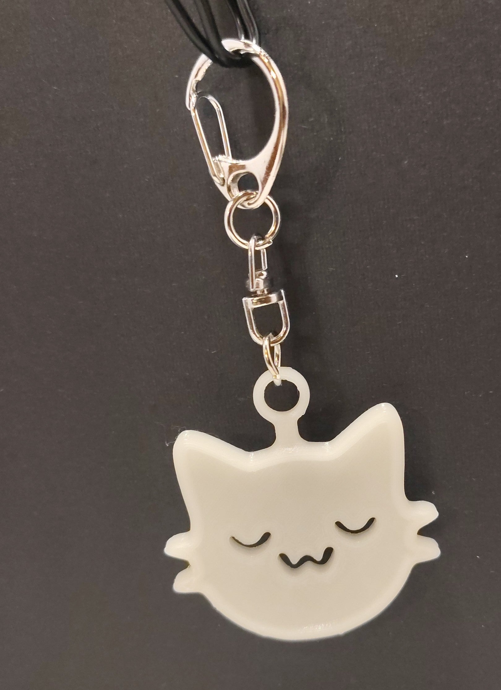 White cat-shaped keychain with a silver swivel clasp on a dark background