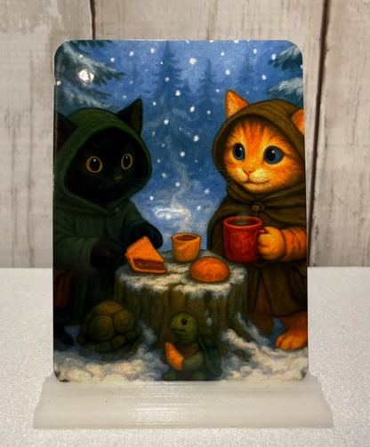 Magnet featuring two adventurer cats and a turtle having a winter picnic.