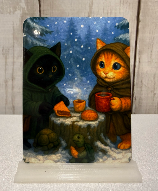 Magnet featuring two adventurer cats and a turtle having a winter picnic.